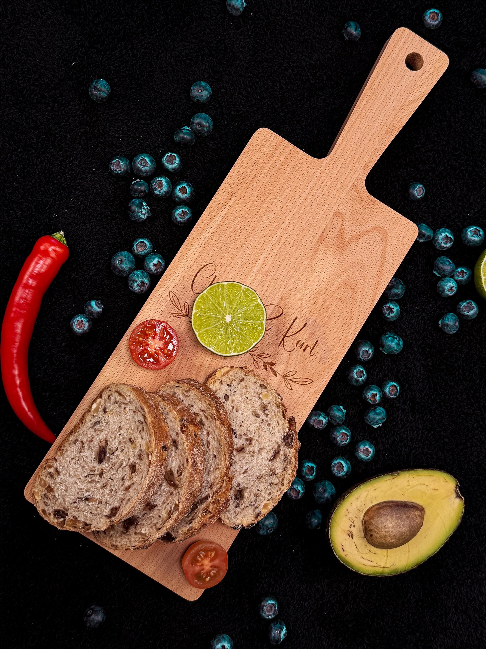 Dekoratives und funktionales Holzbrett mit Griff, ideal zum Schneiden, Servieren oder als stilvolles Geschenk, personalisierbar mit Gravur, geölt und langlebig, perfekt für die Küche oder als Tischdekoration.