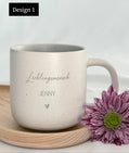 Detailaufnahme der personalisierten Tasse mit individueller Namensgravur. Weiße Keramiktasse mit gesprenkeltem Muster, matter Oberfläche und unglasiertem Boden. Perfekt als Geschenk für Freundin, Kollegin oder als kleine Aufmerksamkeit für besondere Menschen – geeignet für Kaffee, Tee oder heiße Schokolade. Mikrowellen- und spülmaschinenfest. Stilvoll und liebevoll gestaltet.Steingut Tasse . Geschenk für Herzensmensch und Lieblingsmensch
