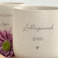 Obenansicht eines personalisierten Tassen-Sets: beige Keramiktasse mit Name auf graviertem Holztablett. Modernes, minimalistisches Design, perfekt als Geschenkidee für besondere Menschen.