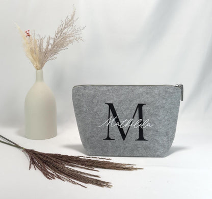 Schminktasche personalisiert mit Namen, hochwertige Struktur und goldfarbenem Reißverschluss, geeignet als individuelles Geschenk für Frauen, Tochter oder beste Freundin, fotografiert neben Make-up-Pinseln und Lippenstift.
