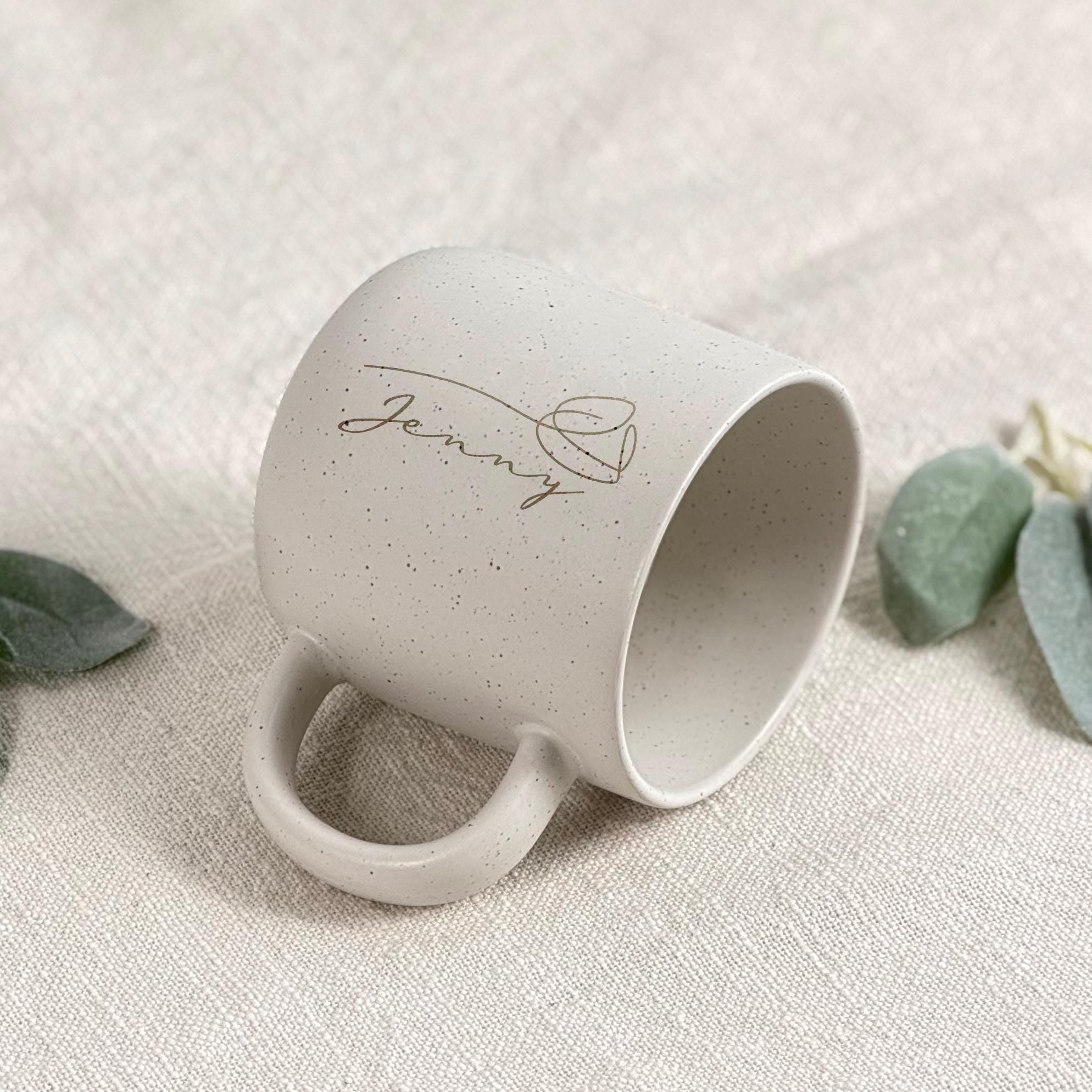 Personalisierte Keramiktasse mit Namen wird in der Hand gehalten – beige, gesprenkelt, 360 ml. Ideal für gemütliche Morgenmomente mit Kaffee oder Tee. Perfektes Geschenk für Freundin, Frau oder Kollegin. Emotionales Produktfoto mit Fokus auf Individualität und Wärme – für besondere Menschen, Abschiede oder kleine Freuden im Alltag. Steingut Tasse beige Personalisierbar