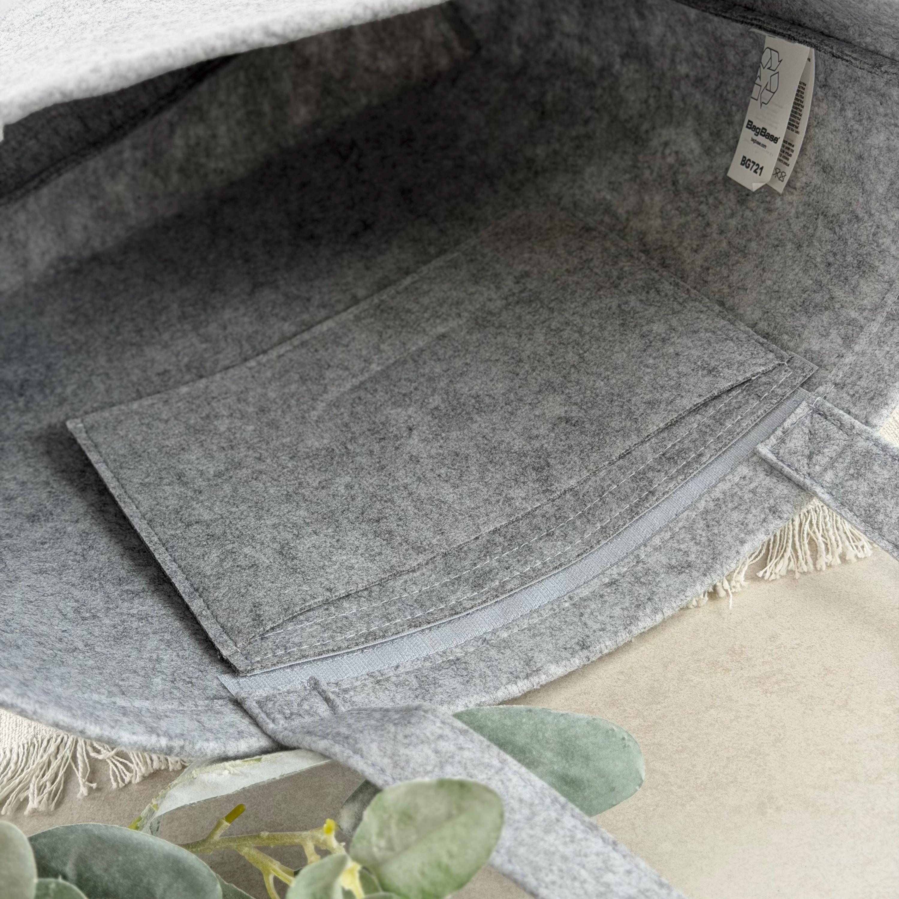 Elegante personalisierte Filztasche, perfekt für Mütter, als Geburtstags- oder Muttertagsgeschenk. Die Tasche ist aus hochwertigem Filz gefertigt und mit Namen oder Wunschtext individuell gestaltet. Auf dem Foto ist die Tasche auf einem Tisch dekoriert mit Herz- und Blumenmotiven. Praktisch für Einkäufe und modisches Accessoire zugleich, ein emotionales Geschenk für Frauen.