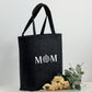 Filztasche für Frauen, personalisiert mit Namen oder individuellem Text, ideal als Geschenk für Mama. Das Bild zeigt die Tasche in einem warmen Licht, umgeben von Deko-Elementen wie Rosen und Geschenkpapier. Perfekt als Muttertagsgeschenk, Weihnachtsgeschenk oder Geburtstagsgeschenk. Die Tasche ist sowohl praktisch als Shopper als auch als dekoratives Accessoire nutzbar.