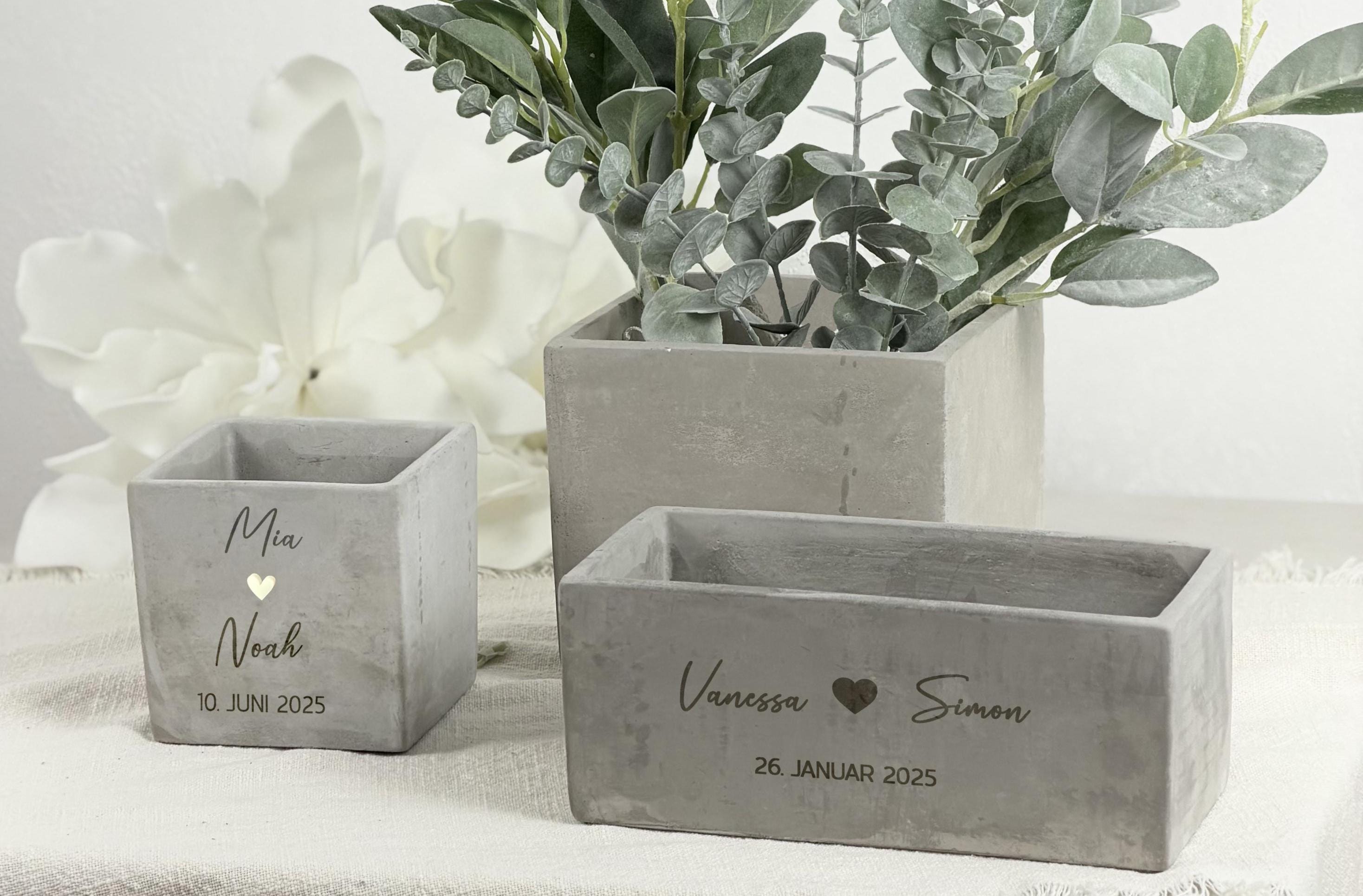 Ein personalisierter Blumentopf mit graviertem Namen des Brautpaars, gestaltet als besonderes Hochzeitsgeschenk. Der Topf zeigt eine elegante Oberfläche, einen warmen Naturton und eine liebevolle Gravur mit Herzen und Datum. Eine kleine Pflanze sitzt dekorativ im Inneren. Ideal als Geldgeschenk-Idee oder Einweihungsgeschenk, perfekt für Paare, die ein stilvolles und persönliches Dekostück für ihr neues Zuhause suchen.