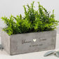 Personalisierter Pflanztopf für Paare, darauf fein gravierte Namen und ein romantischer Spruch. Der Blumentopf steht auf einer hellen Holzfläche und wird von einer kleinen grünen Pflanze ergänzt. Ein ideales Hochzeitsgeschenk, Einzugsgeschenk oder Geschenk zur Verlobung. Das moderne, minimalistische Design macht ihn zu einer zeitlosen Deko-Idee für Wohnzimmer, Küche oder Balkon.