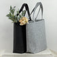 Eine robuste, stilvolle Filztasche für Frauen, personalisiert mit Namen oder Wunschtext. Die Tasche wird als perfektes Mama Geschenk präsentiert, ideal für Geburtstage, Muttertag oder Weihnachten. Das Bild zeigt die Tasche in einem hellen, gemütlichen Umfeld, dekoriert mit Blumen, Kerzen und Accessoires, um die Einzigartigkeit und Bedeutung des personalisierten Geschenks zu unterstreichen.