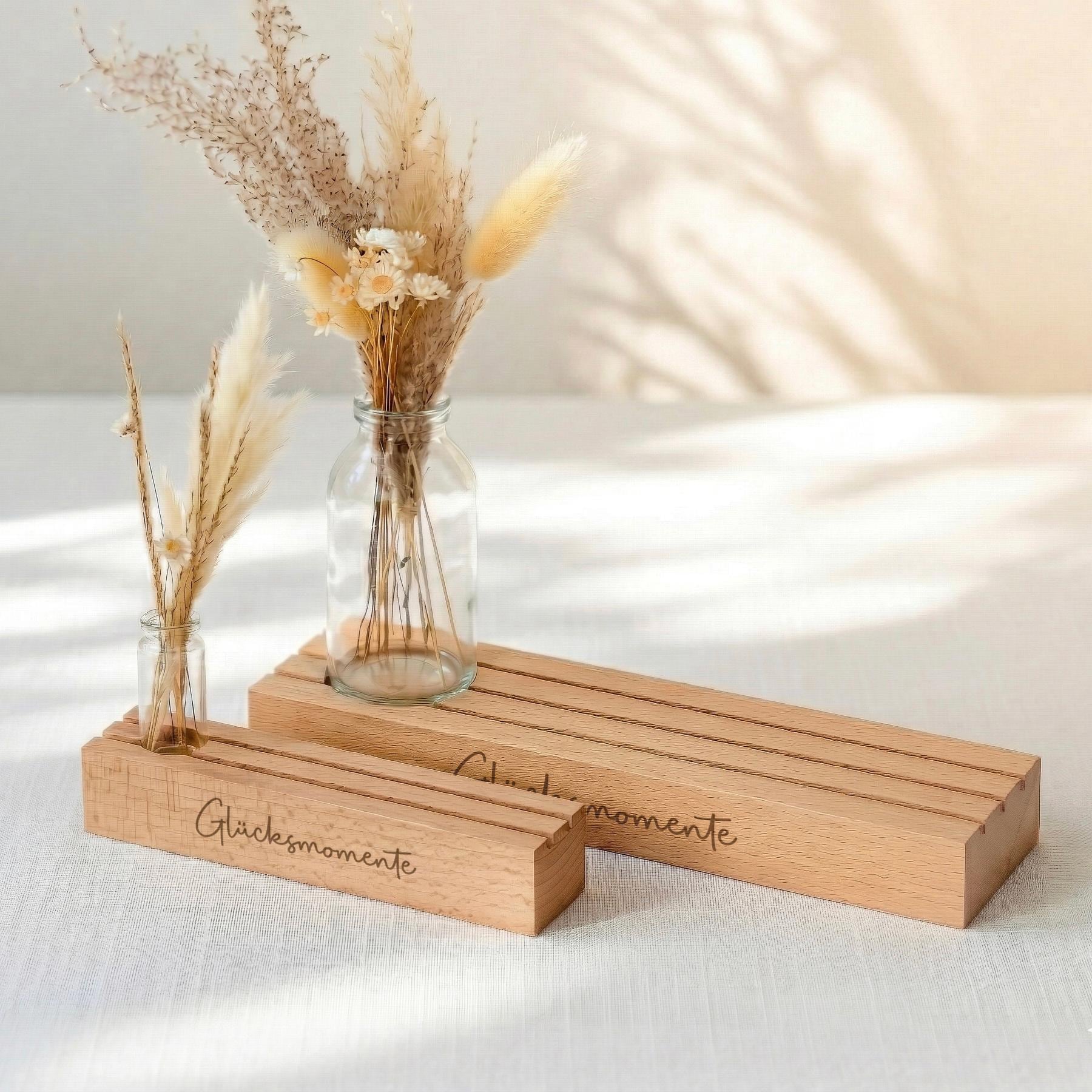 Fotohalter personalisiert mit Vase und Trockenblumen sowie Gravur Glücksmomente. Diese Bilderleiste individuell aus Buchenholz ist ideal als Geschenk für Mama, Oma oder als Muttertag Geschenk. Der Kartenständer mit Gravur präsentiert Fotos stilvoll und dient gleichzeitig als Kerzenhalter Deko. Perfekt als Geburtstagsgeschenk Frau oder Tischdeko Geburtstag mit natürlicher Holzoptik.