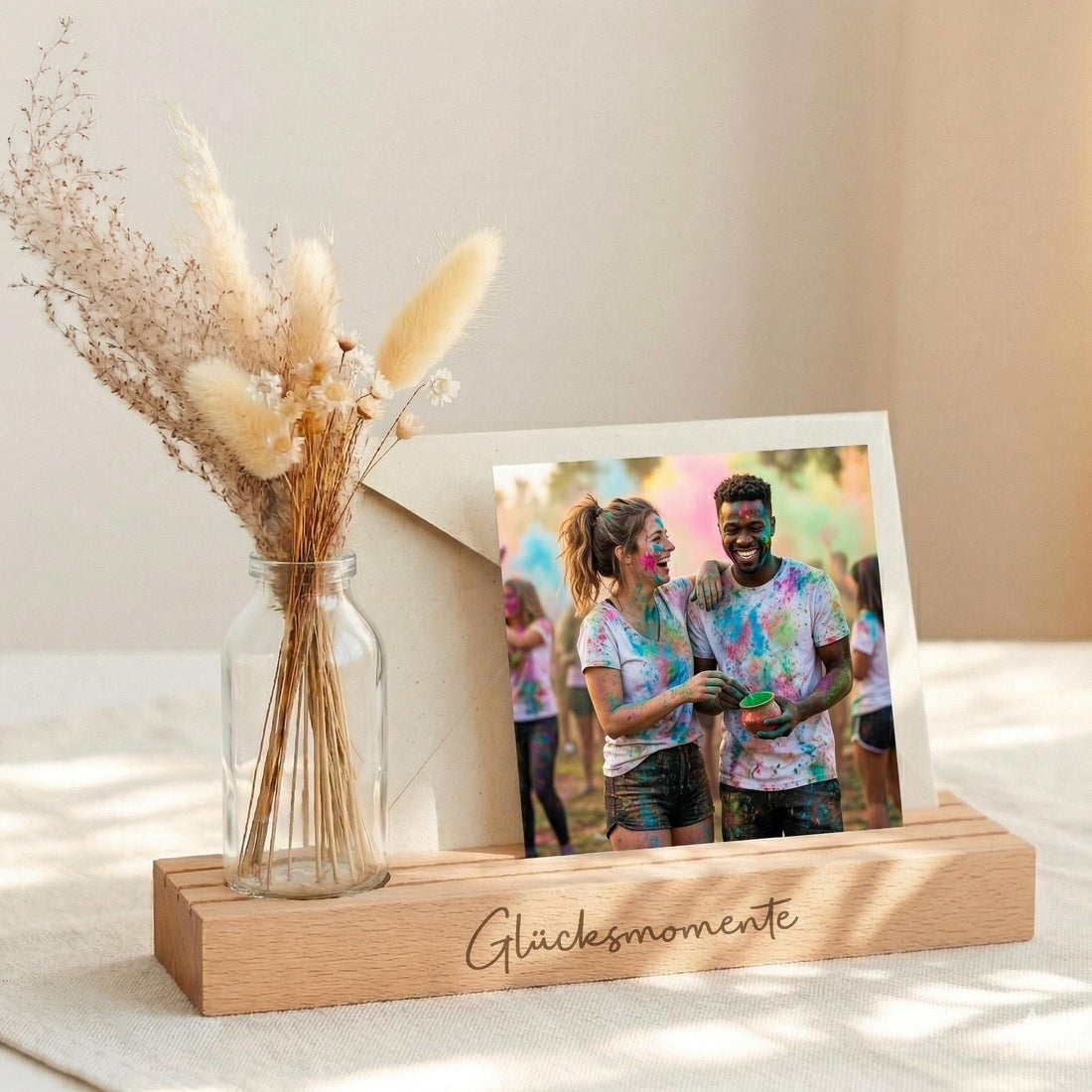 Fotoleiste mit Spruch Glücksmomente als Kartenhalter personalisiert mit Vase und Trockenblumen. Der Fotoständer personalisiert aus Buchenholz ist ein liebevolles Geschenk für Mama oder Oma. Perfekt als Muttertag Geschenk oder Geburtstagsgeschenk Frau. Diese Bilderleiste individuell kombiniert Kartenständer mit Gravur und Kerzenhalter Deko und eignet sich ideal als Tischdeko Geburtstag mit natürlicher Holzdekoration.