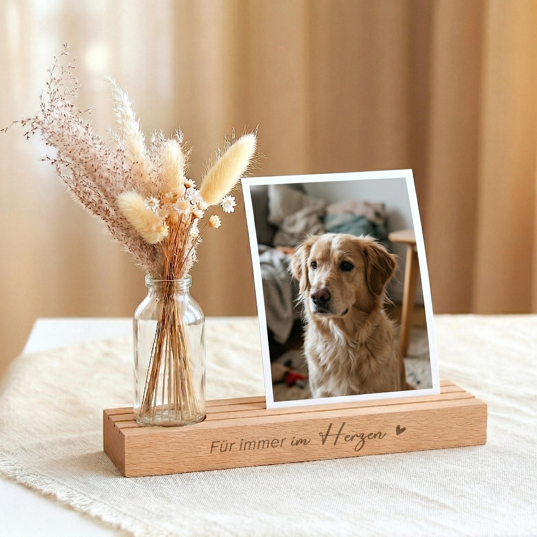 Fotohalter personalisiert als einfühlsames Trauergeschenk individuell gestaltet mit Vase und Trockenblumen. Die Bilderleiste Bilderrahmen aus hochwertigem Buchenholz trägt die Gravur „Für immer im Herzen“ und bietet Platz für Fotos, Erinnerungen oder Kondolenzkarten. Der Kartenständer mit Gravur dient gleichzeitig als Kerzenhalter für eine Gedenkkerze und schafft einen ruhigen Ort des Erinnerns. Ideal als Kondolenzgeschenk Beileid, Geschenk Anteilnahme oder stilvolle Dekoration zur Beerdigung.