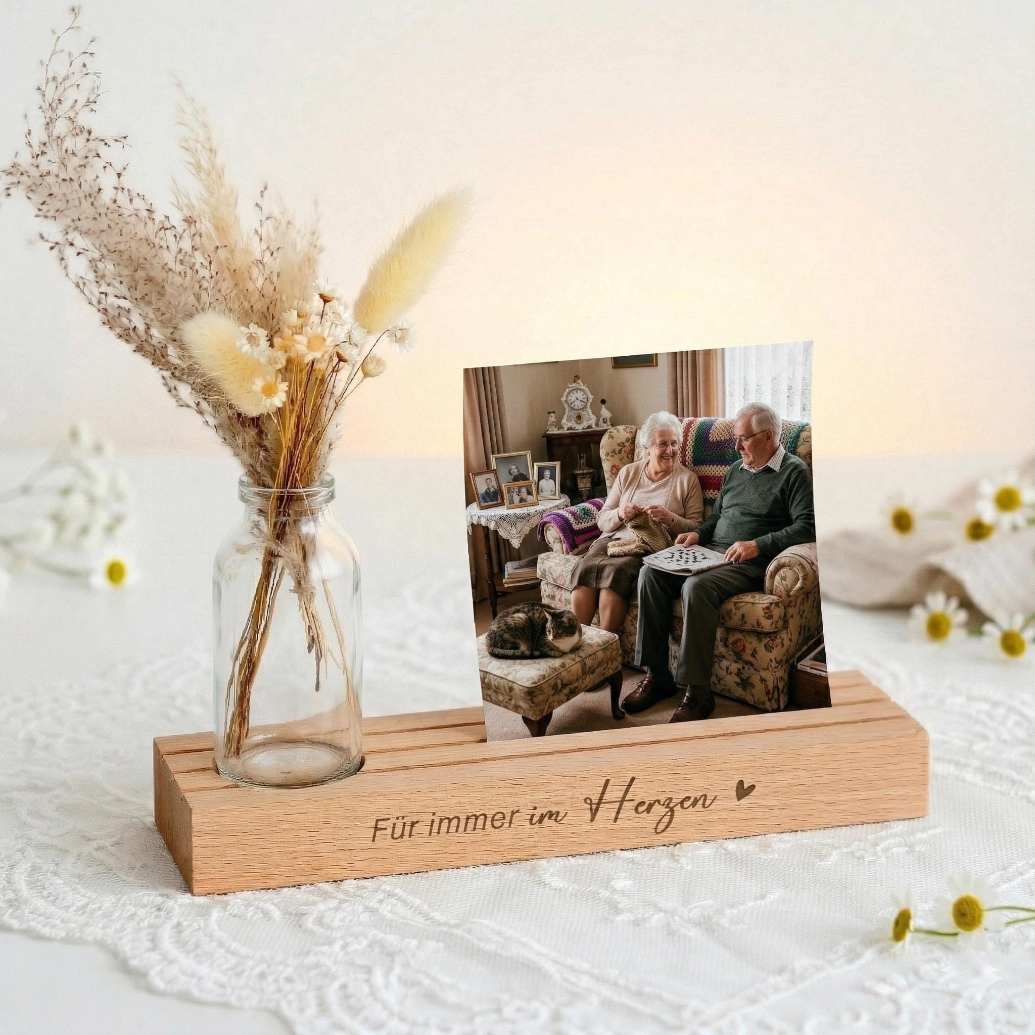 Fotoständer personalisiert als Gedenkseite mit Vase und Trockenblumen. Diese Bilderleiste aus Buchenholz mit Gravur „Für immer im Herzen“ ist ein liebevolles Trauergeschenk individuell gestaltet. Kartenhalter personalisiert für Fotos und Kondolenzkarten. Kerzenhalter für Gedenkkerze ergänzt das Geschenkset Beileid Erinnerung und eignet sich als Kondolenzgeschenk Beileid oder Geschenk Anteilnahme.