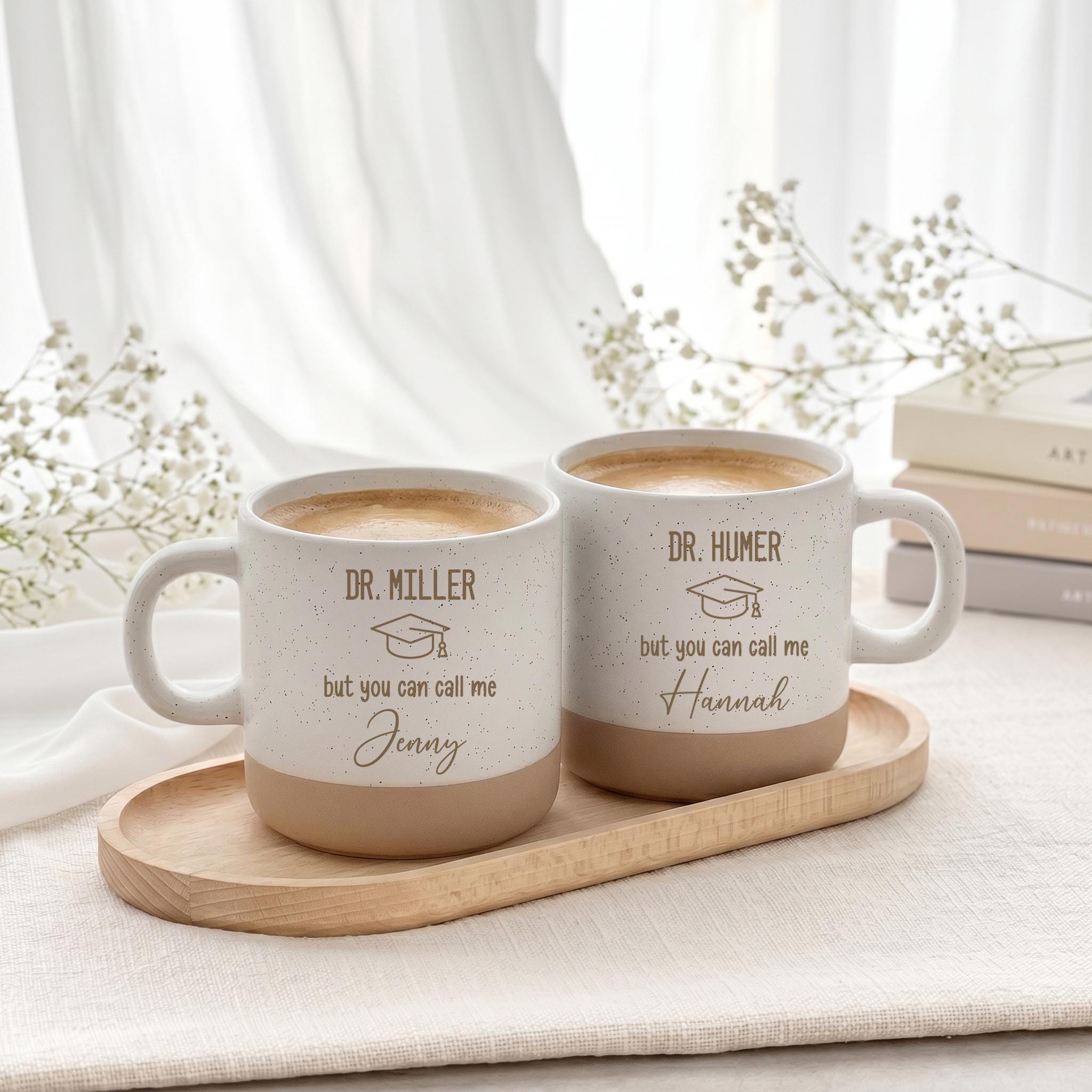 Hochwertige personalisierte Tasse mit eleganter Gravur als Geschenk zur Promotion und zum bestandenen Doktortitel. Die individuelle Gestaltung mit Namen macht diese Keramiktasse zu einem besonderen Erinnerungsstück für Absolventinnen und Absolventen nach vielen Jahren harter Arbeit.